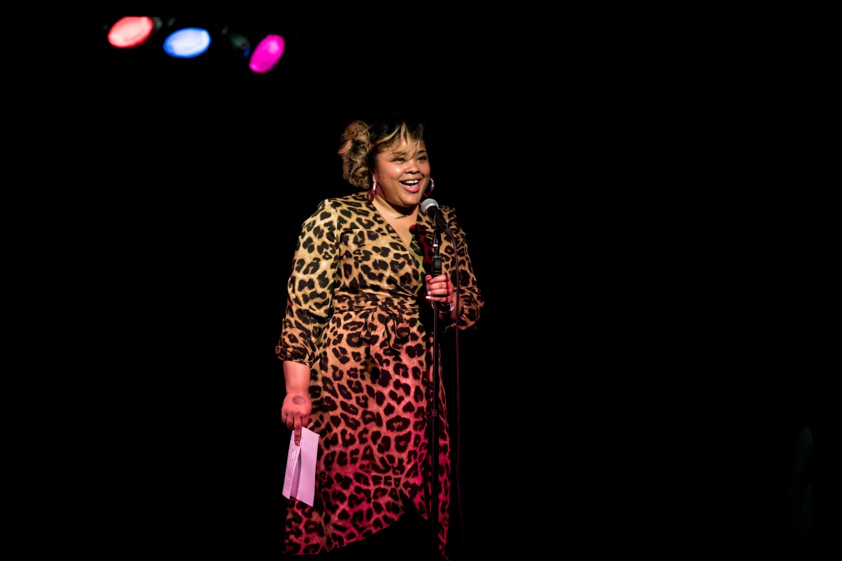 Diana Veiga laughing at the mic in a leopard-print dress