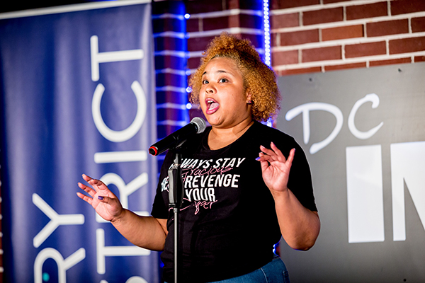 Diana Veiga performing at the mic with Story District at the DC Improv